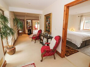 A bedroom with a bed, a desk, two chairs, a potted plant, a painting, and a mirror. - Meadow View Bungalow (Droitwich)