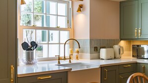 Una cocina con ventana, un fregadero, una tetera y un tostador.