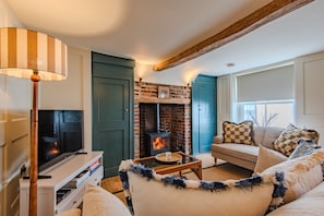 Ein gemütliches Wohnzimmer mit Kamin, Fernseher und einer Couch.