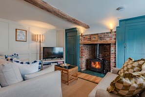 Ein gemütliches Wohnzimmer mit Kamin, Fernseher und bequemen Sitzgelegenheiten.