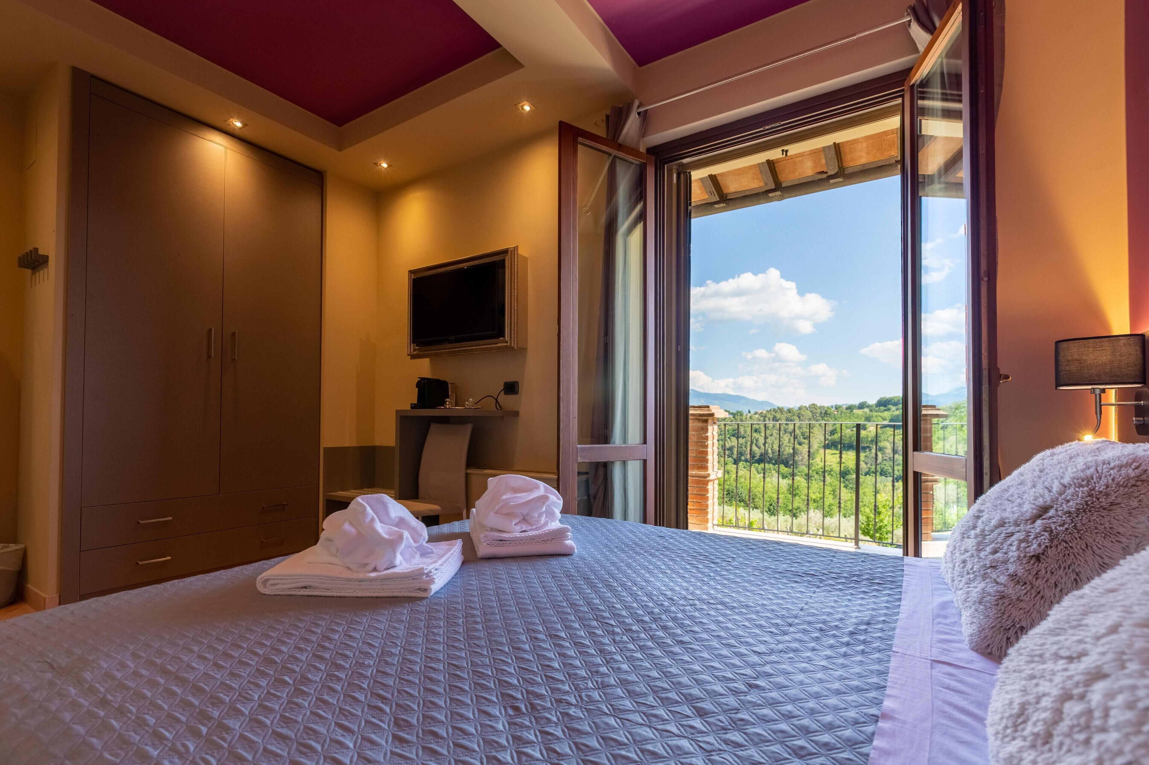 Ein Schlafzimmer mit einem großen Bett, einem Fernseher und einem Balkon mit Blick.
