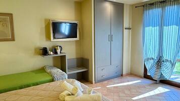 Une chambre à coucher avec un lit, une télévision, une armoire et une fenêtre avec des rideaux.