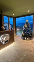 A reception area with a large Christmas tree, a sheep-shaped light fixture, and a view of a cityscape at dusk.