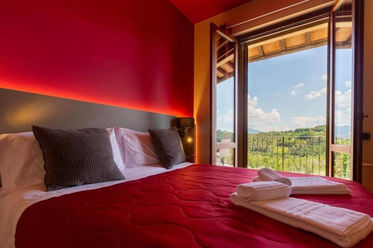 Una habitación de hotel con una cama grande, vistas a un paisaje verde y un balcón.