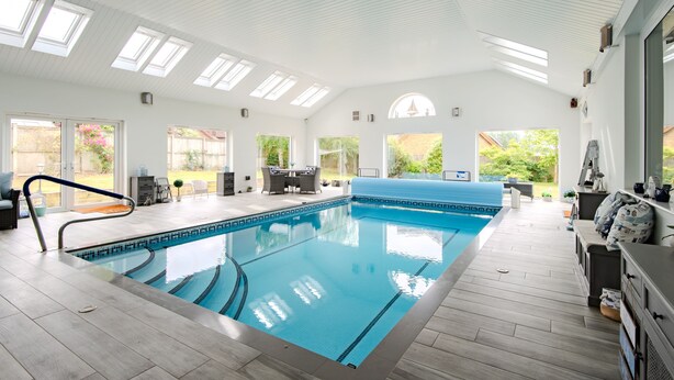 Una piscina interior con tragaluces, una terraza solárium y un solárium con vistas.