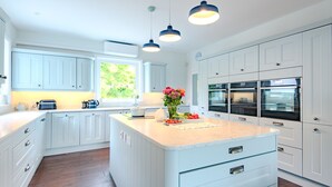 Una cocina con armarios blancos, encimera de mármol e iluminación colgante.
