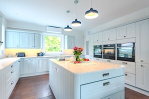 Una cocina con armarios blancos, encimera de mármol e iluminación colgante.