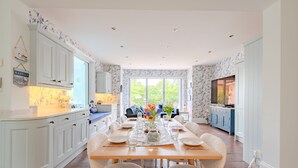 Una cocina amplia con comedor, armarios blancos y un ventanal que proporciona luz natural.