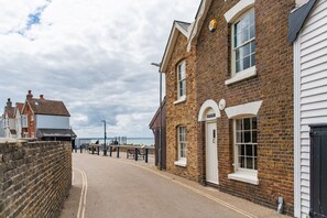 A street with a brick building, a bench, and a wall. - The Cottage, Whitstable (Whitstable)