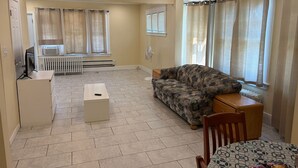 Una sala de estar con un sofá, un televisor, una mesa con aperitivos y un radiador.