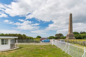 A monument, a fenced area, a building, and a blue car.