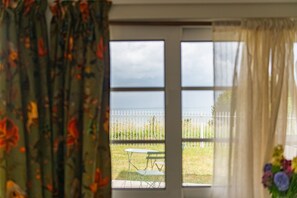 A room with a view through a window, a table, and a chair outside.