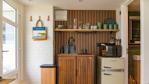 A compact kitchen with a wooden cabinet, a vintage refrigerator, and a window with a view.