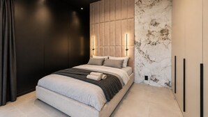A modern bedroom with a bed, headboard, and a marble-patterned wall.
