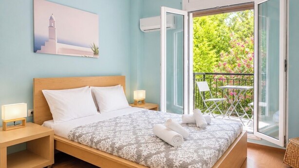 Ein Schlafzimmer mit Bett, Nachttischen, einem Fenster und einem Balkon mit Geländer.