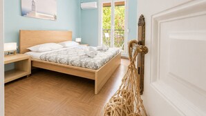 Ein Schlafzimmer mit einem hölzernen Bett, einem Nachttisch, einer Wand-Klimaanlage und Blick auf Grünfläche.