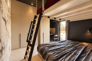 Ein Schlafzimmer mit einem Bett, einer Leiter, einem Schreibtisch und einem Stuhl.