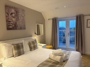 Quarto de hotel com cama, uma janela grande com cortinas, varanda e uma obra de arte na parede.