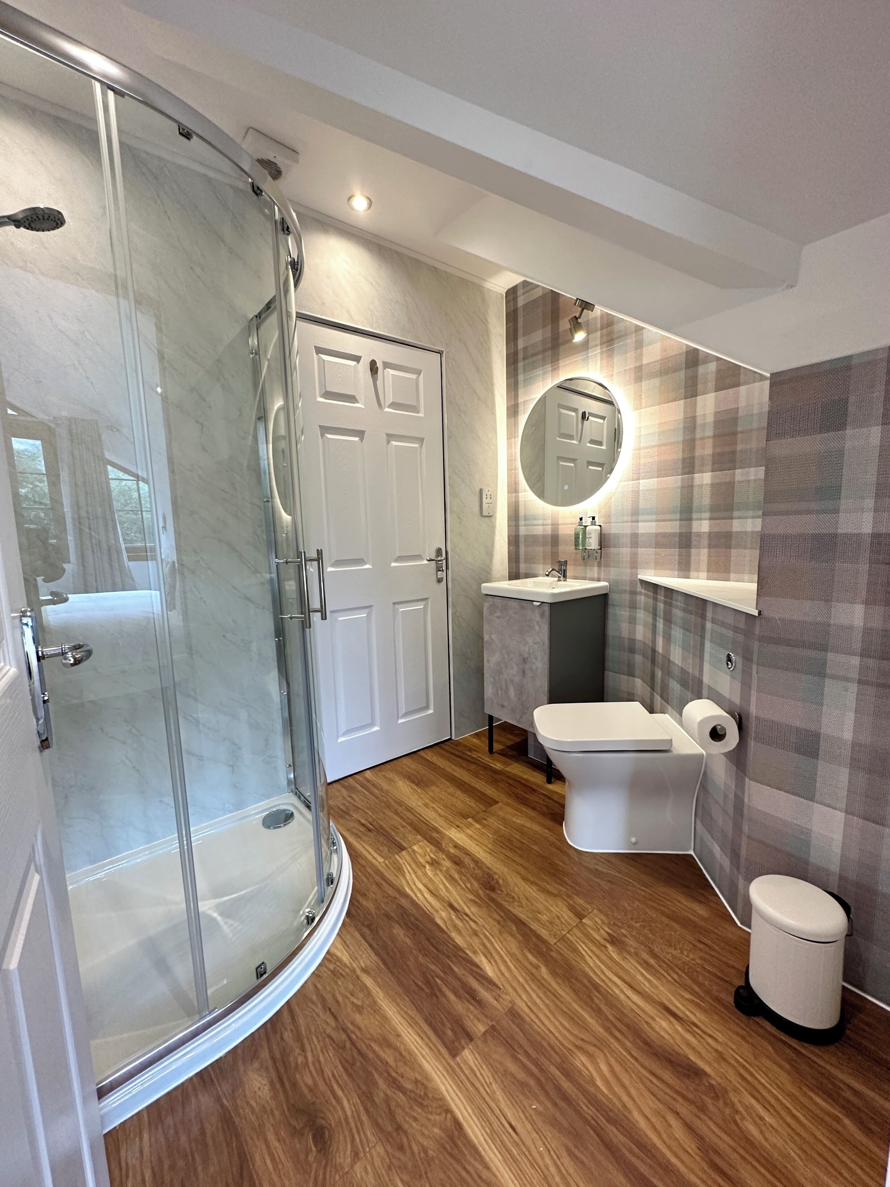 A modern bathroom with a glass shower enclosure, a toilet, and a sink.