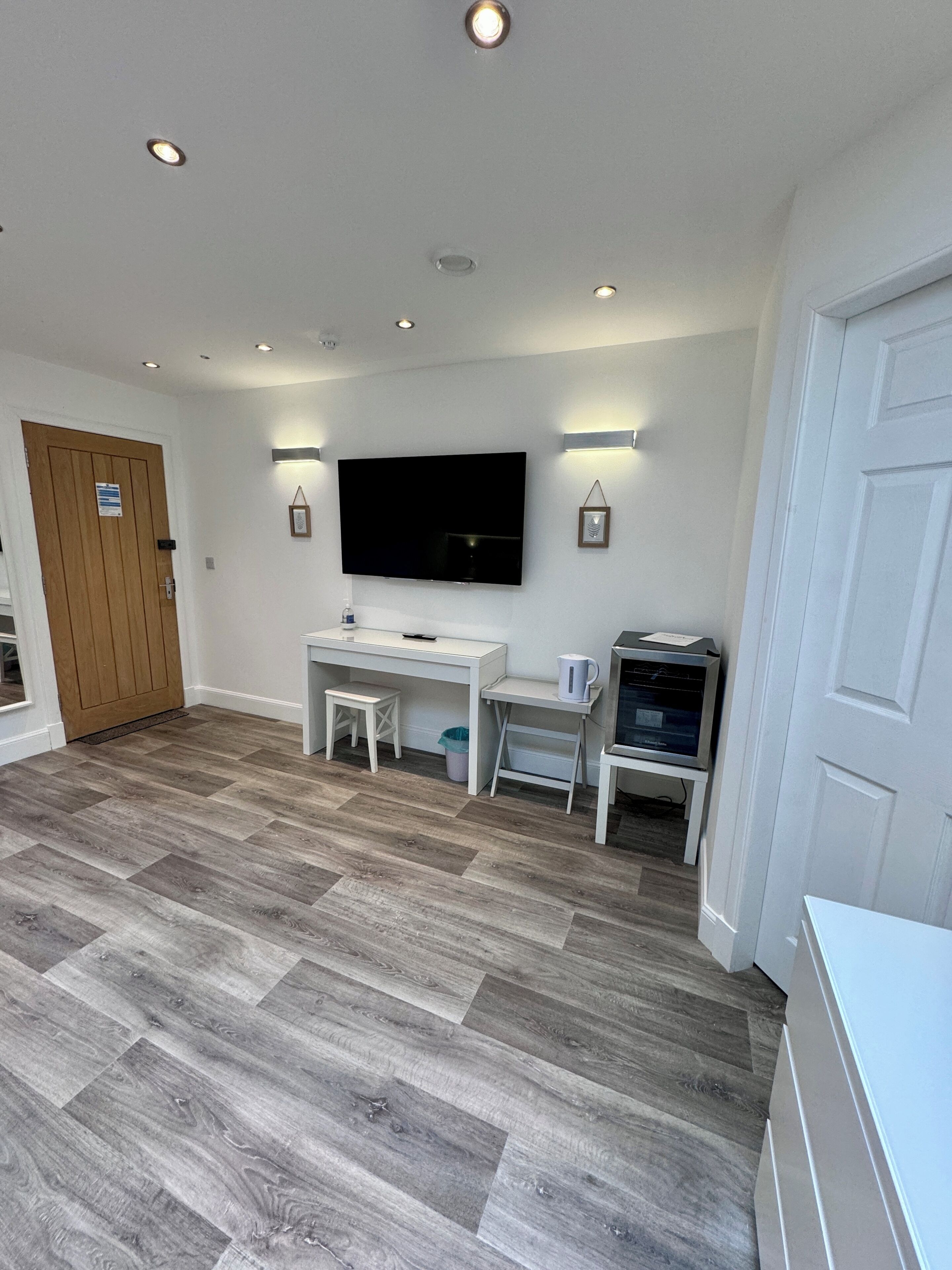 A modern room with a flat-screen TV, white furniture, and a herringbone-patterned floor.