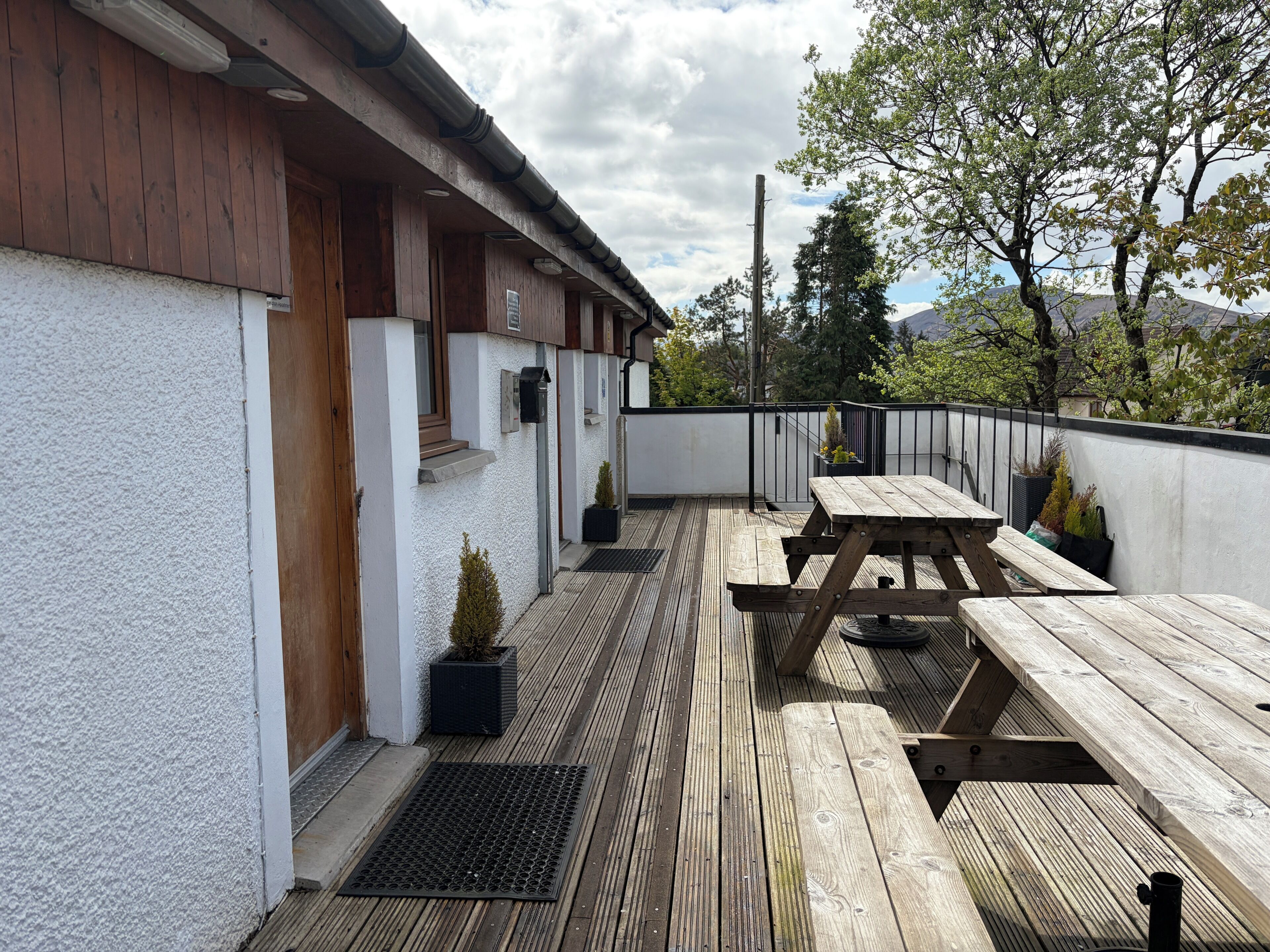 A wooden deck with a picnic table and potted plants.
