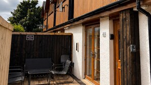 A wooden building with a deck, outdoor seating, and a door with a glass panel. - Sheraton Apartments (Fort William)