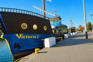 Ein vertäutes Schiff namens 'Victoria I' bei blauem Himmel und ruhiger Wasserfläche.