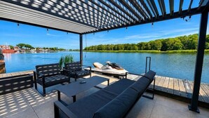 A covered outdoor seating area with a view of a lake and dock. - Charming Dziwnów House with a jacuzzi (Dziwnów)