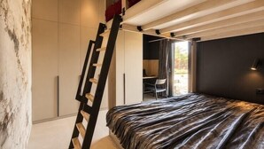 Ein Schlafzimmer mit einem Bett, einer Leiter, einem Schreibtisch und einem Stuhl.