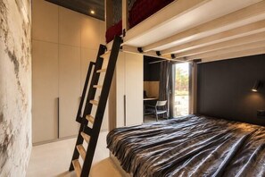 Ein Schlafzimmer mit einem Bett, einer Leiter, einem Schreibtisch und einem Stuhl.