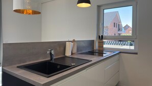 Ett modernt kök med en svart diskho, vita skåp och hängande lampor.