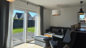 Ett modernt vardagsrum med en soffa, en pall och en matplats med bord och stolar.