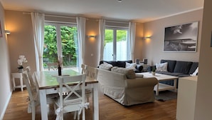 A modern living room with a dining area, a sofa set, and a painting on the wall.