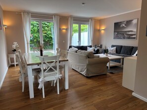 A modern living room with a dining area, a sofa set, and a painting on the wall.
