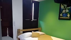 Una cama individual con estructura de madera, una mesita de noche y un pequeño armario blanco.