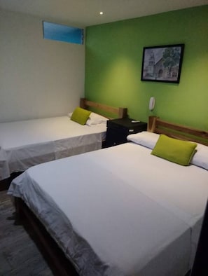 A hotel room with two single beds, each with a green pillow and white bedding. - Hotel Cañaveral Plaza (Manizales)