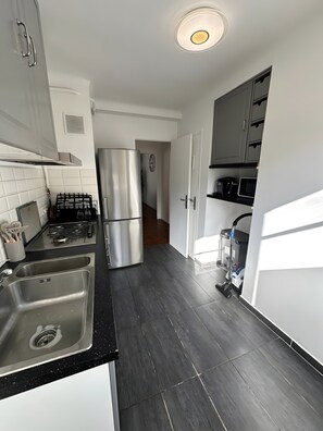 Una cucina moderna con elettrodomestici in acciaio inossidabile, un piano di lavoro nero e un pavimento in legno scuro.