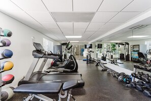 Une salle de sport équipée de tapis de course, d’appareils de musculation et de poids libres.