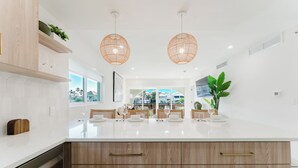 A modern kitchen with a large island, pendant lights, and a view to the dining area. - Villa Arcata: 2BR Boca Water Suite (Boca Raton)