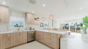 A modern kitchen with wooden cabinets, white countertops, and pendant lighting. - Villa Arcata: 2BR Boca Water Suite (Boca Raton)