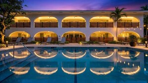 A hotel with a pool, multiple balconies, and a sunset sky. - Villa Arcata: 2BR Boca Water Suite (Boca Raton)