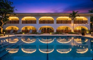 Ein Hotel mit Pool, mehreren Balkonen und einem Sonnenuntergangshimmel.