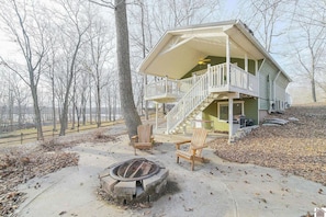 A cabin with a covered porch, a fire pit, and a chair. - Beautiful Cottage on the water with a dock for lake access! Quiet and cozy! (Benton)