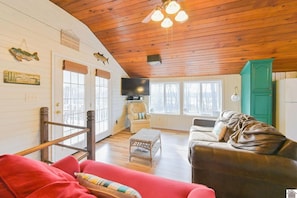 A cozy cabin interior with a wooden ceiling, a television, a leather sofa, and a red couch. - Beautiful Cottage on the water with a dock for lake access! Quiet and cozy! (Benton)