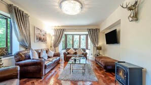Ein geräumiges Wohnzimmer mit Ledersofas, einem Glastisch und einem Kamin.