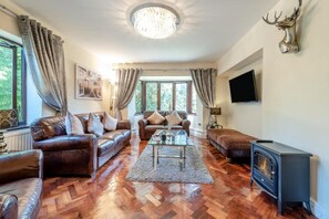 A spacious living room with leather sofas, a glass coffee table, and a fireplace. - Apartment - Sleeps 6 - Private Garden (Swansea)