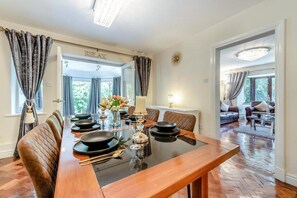 A dining area with a wooden table set for four, flanked by leather chairs. - Apartment - Sleeps 6 - Private Garden (Swansea)