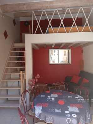 Ein Essbereich mit Tisch, Stühlen, einer Treppe und einer roten Wand.