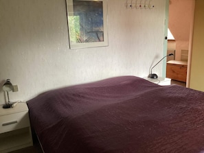 A bedroom with a bed, a nightstand, a lamp, a dresser, and a framed picture on the wall. - 6 Person Holiday Home in Bandholm (Bandholm)