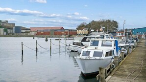 A marina with boats docked, a wooden pier, and industrial buildings in the background. - 6 Person Holiday Home in Bandholm (Bandholm)